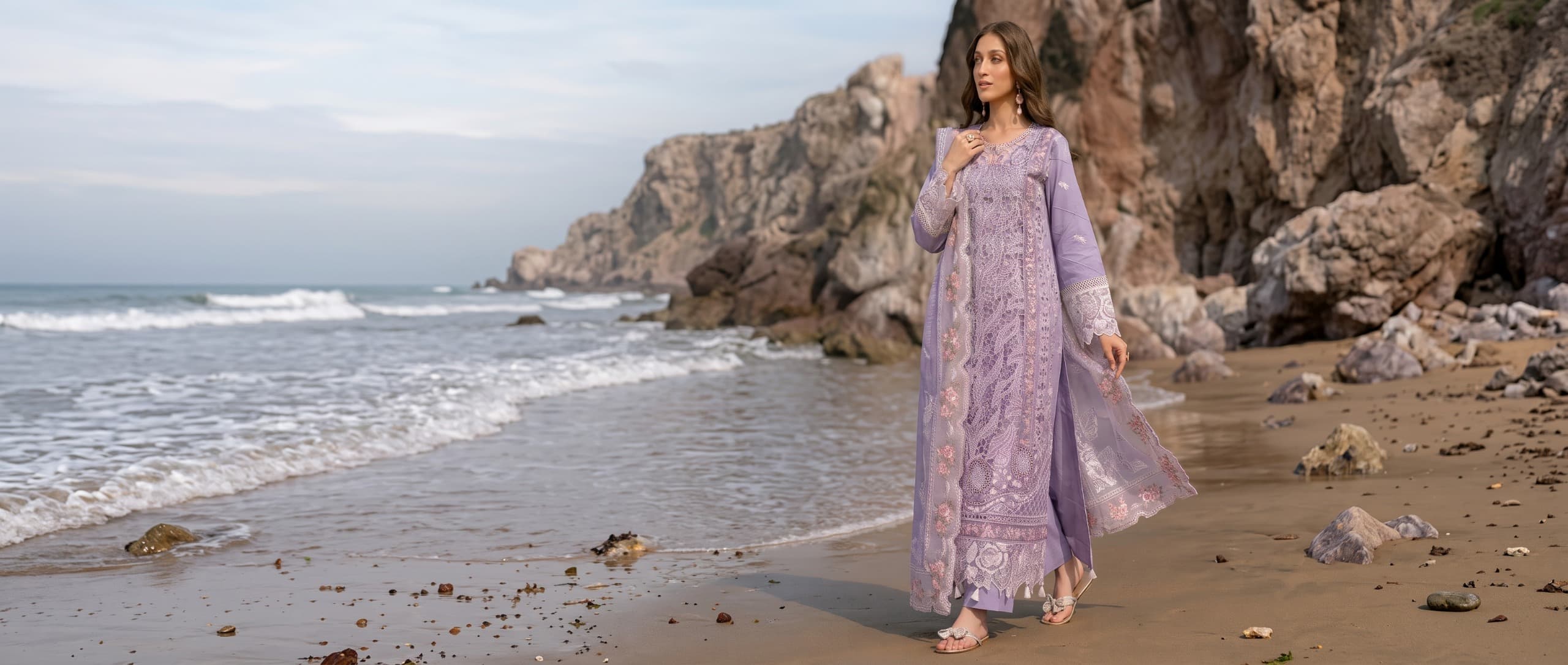 Model in lilac embroidered suit on a beach