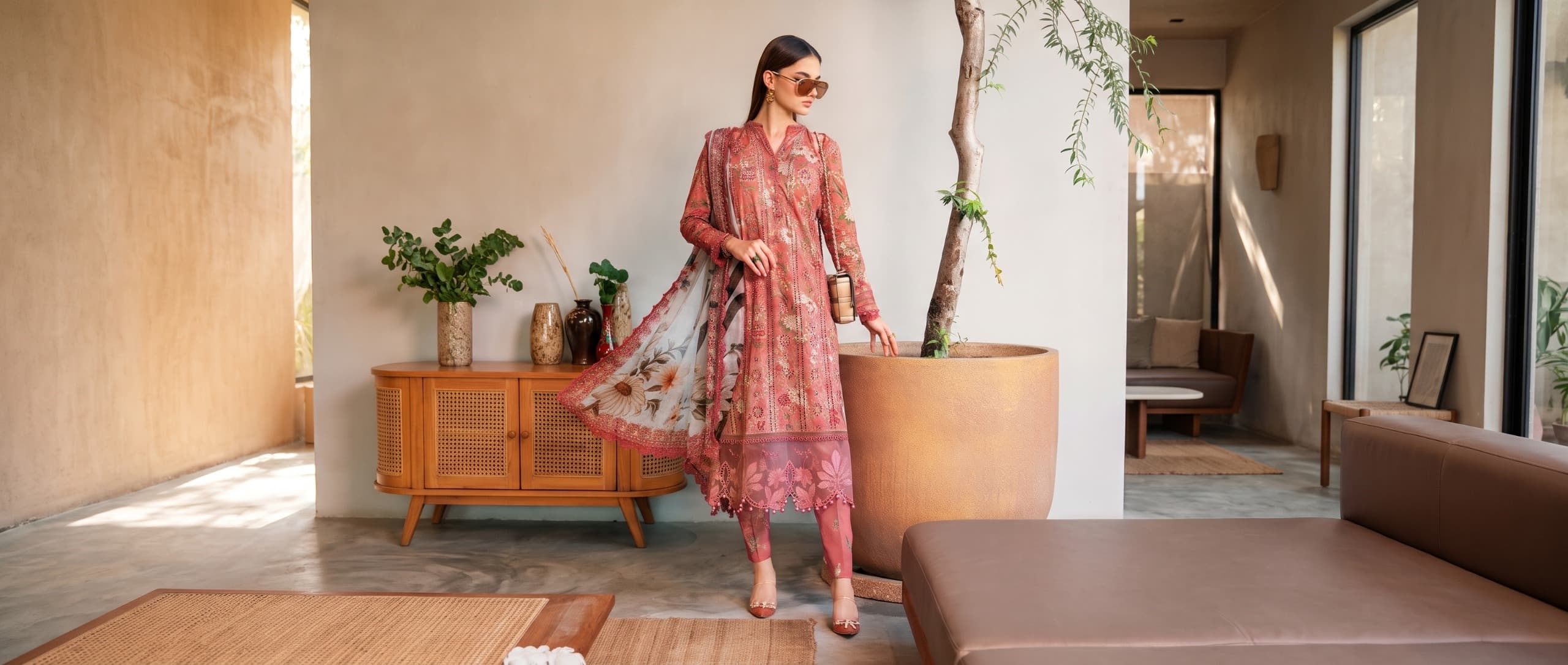 Model in coral printed suit in a sunlit room
