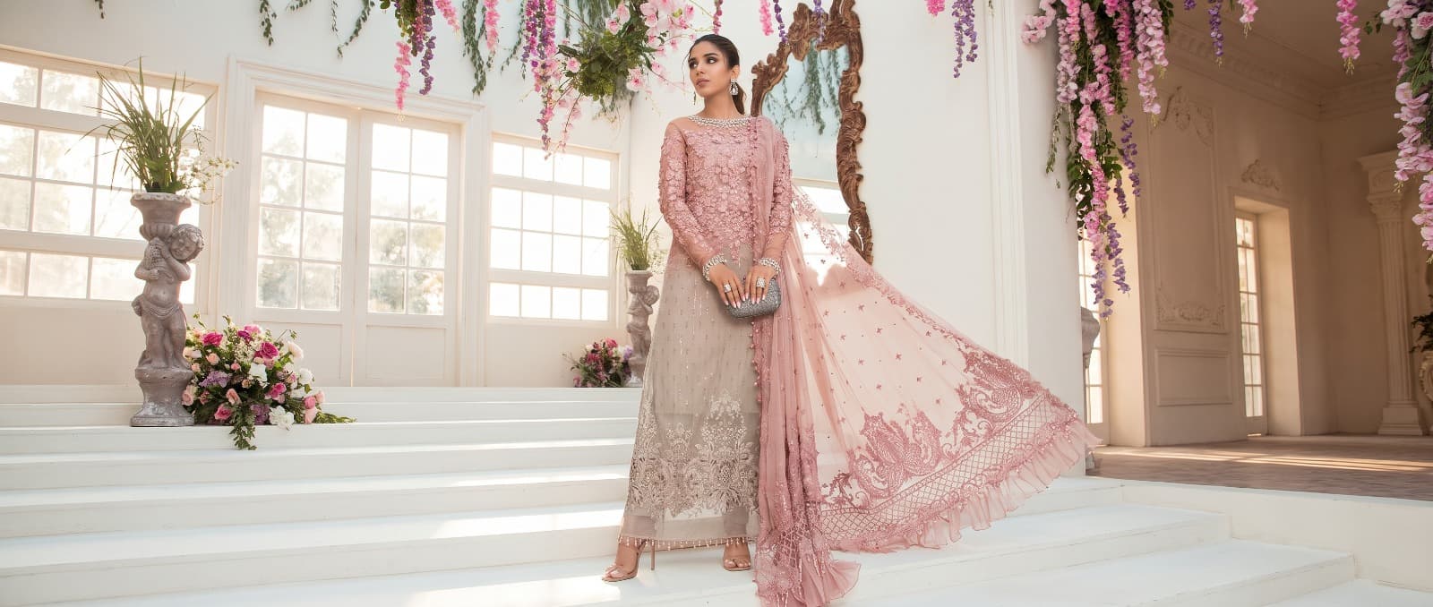 Model in blush formal with flowing dupatta on white stairs